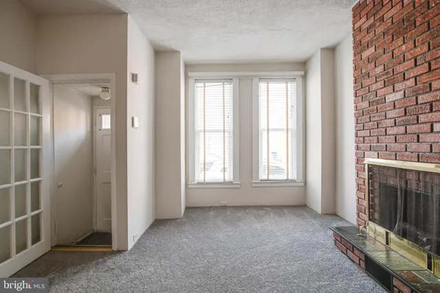 an empty room with windows and fireplace