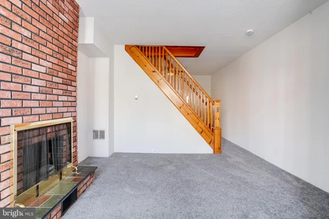 a view of an empty room with wooden floor and stairs