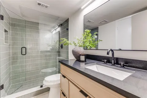 a bathroom with a granite countertop sink a toilet and shower