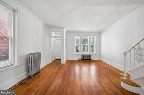 a view of an empty room with wooden floor and window