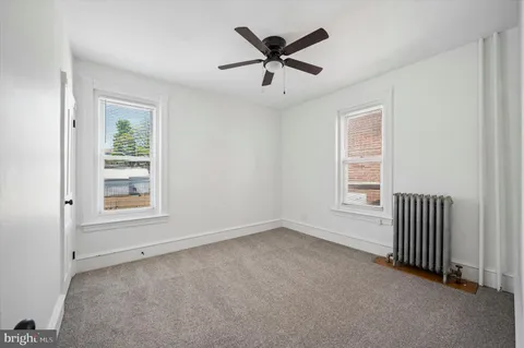 an empty room with ceiling fan and windows