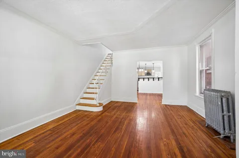 a view of an empty room with wooden floor and stairs