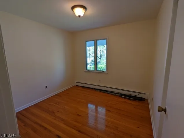 an empty room with wooden floor cabinet and windows