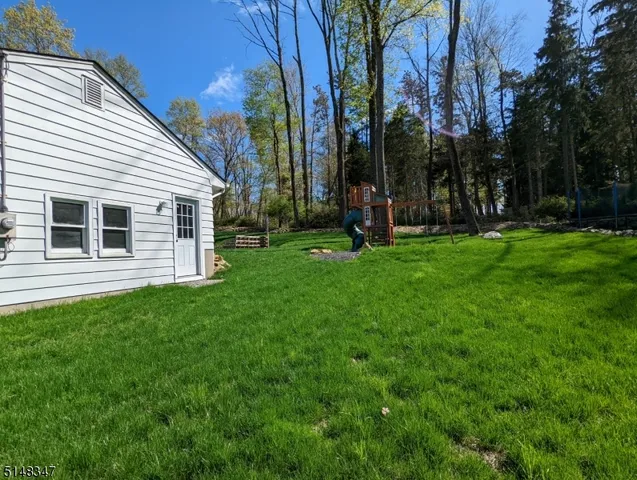 a backyard of a house with plants and large tree
