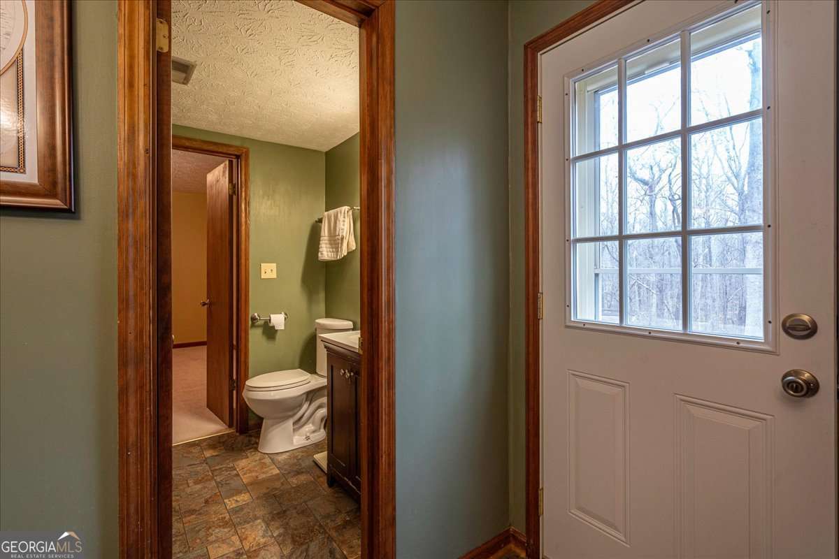 59 Busbin Lane Colbert, GA 30628 - Photo 18 of 29 a bathroom with a granite countertop toilet a sink and a large mirror