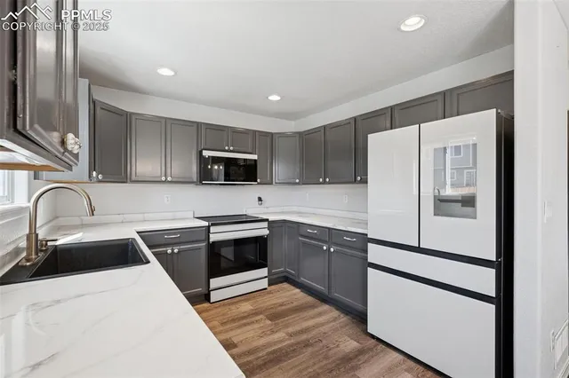 a kitchen with stainless steel appliances granite countertop a refrigerator sink and white cabinets