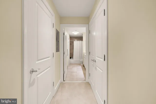 a view of a hallway with wooden floor and a bathroom