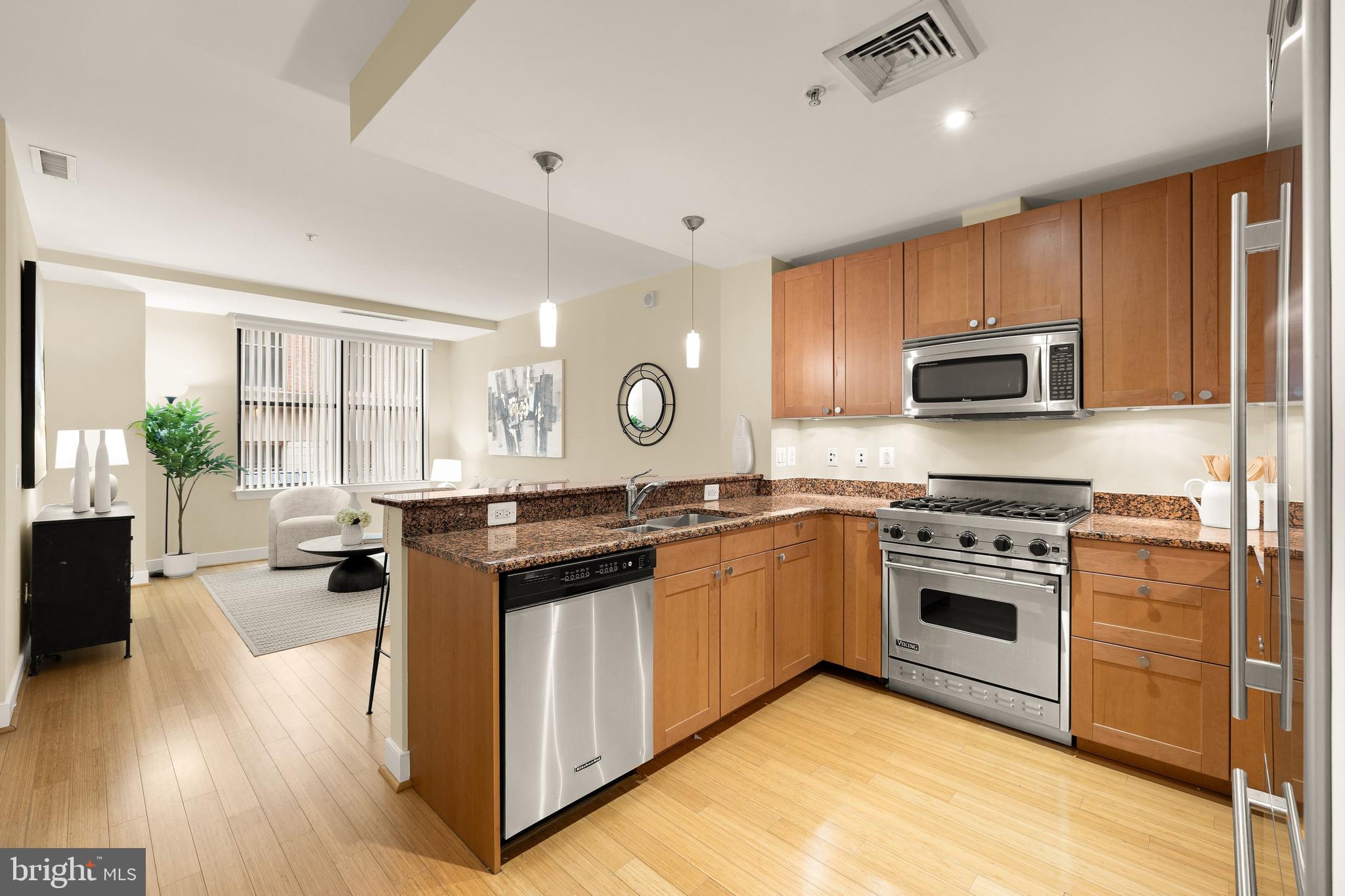 2425 L Street Northwest, Unit 234 Washington, DC 20037 - Photo 4 of 23 a kitchen with stainless steel appliances granite countertop a stove top oven a sink dishwasher and a microwave oven with wooden floor