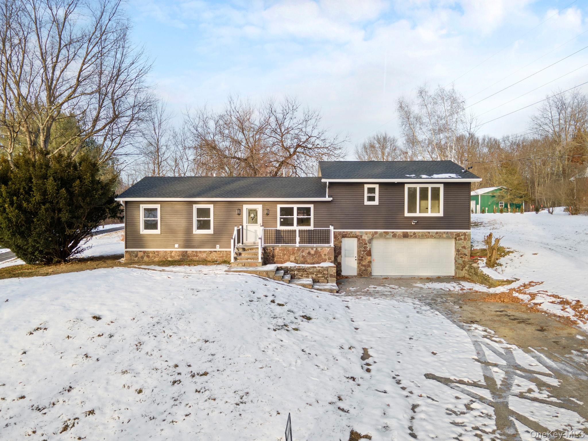 Tri-level home featuring an attached garage and stone siding