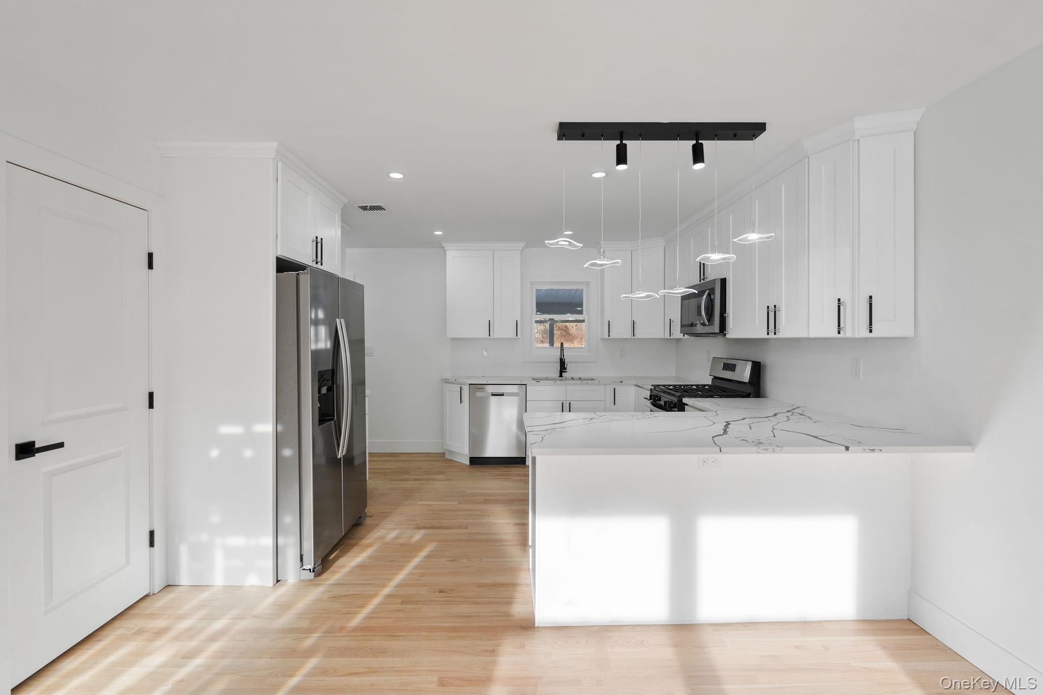 52 Rudolph Road Modena, NY 12548 - Photo 8 of 46 Kitchen with white cabinets, stainless steel appliances, decorative light fixtures, light stone countertops, and a peninsula