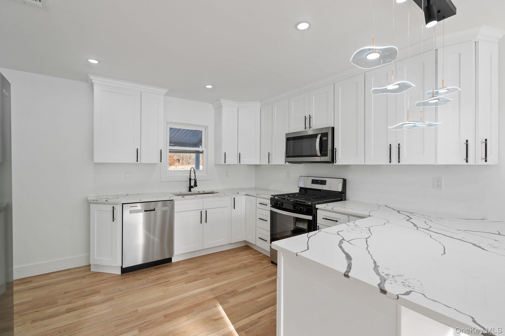 52 Rudolph Road Modena, NY 12548 - Photo 9 of 46 Kitchen featuring appliances with stainless steel finishes, light stone countertops, white cabinets, decorative light fixtures, and light wood-style flooring
