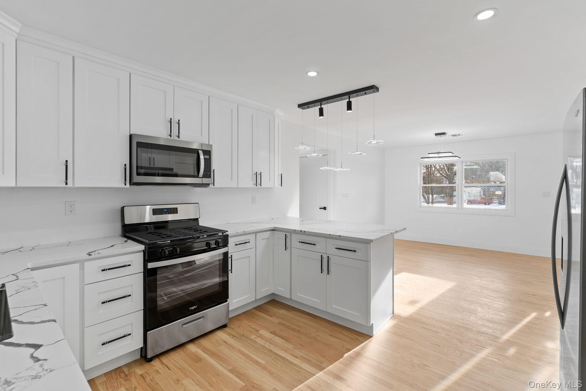 52 Rudolph Road Modena, NY 12548 - Photo 10 of 46 Kitchen featuring stainless steel appliances, decorative light fixtures, white cabinetry, light stone countertops, and light wood-type flooring
