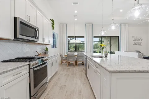 a kitchen with stainless steel appliances granite countertop a stove a sink and a microwave