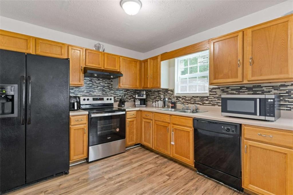 1450 Steam Engine Way Northeast Conyers, GA 30013 - Photo 7 of 33 a kitchen with stainless steel appliances granite countertop a stove a sink dishwasher a refrigerator and cabinets with wooden floor