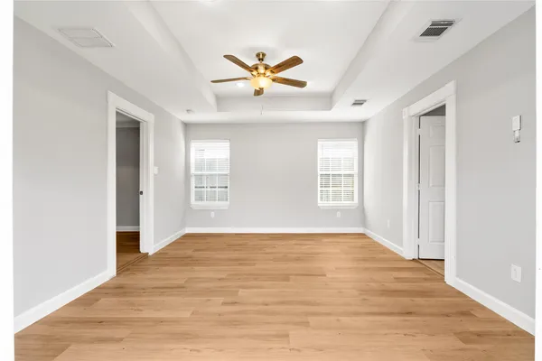 a view of an empty room with window and wooden floor