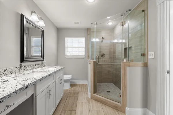 a bathroom with a shower sink vanity granite and mirror
