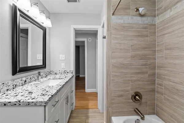 a bathroom with a granite countertop sink a mirror and shower