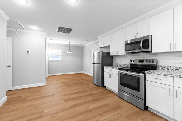 a kitchen with stainless steel appliances white cabinets a sink a stove a microwave and a refrigerator