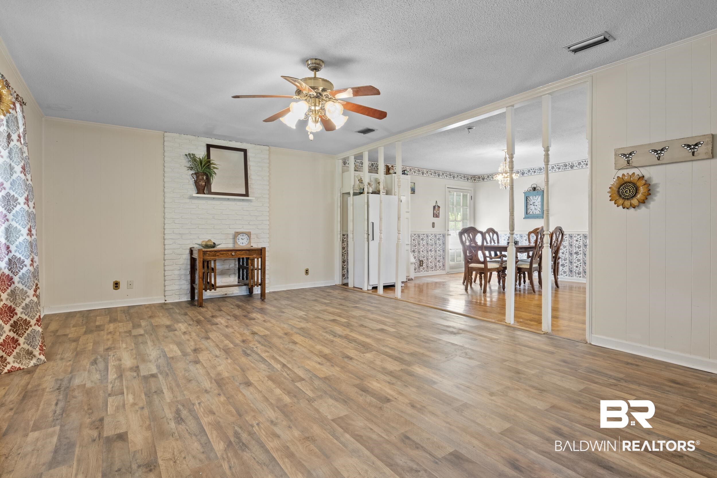 8701 A Rosemary Road Eight Mile, AL 36613 - Photo 11 of 27 Unfurnished living room with ceiling fan, wood-type flooring, a textured ceiling, and brick wall