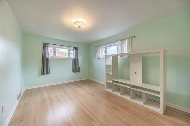 an empty room with wooden floor closet and windows