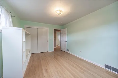 a view of an empty room with closet and a window