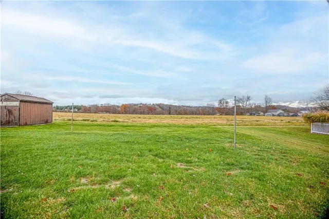 a view of a house with a big yard and large trees