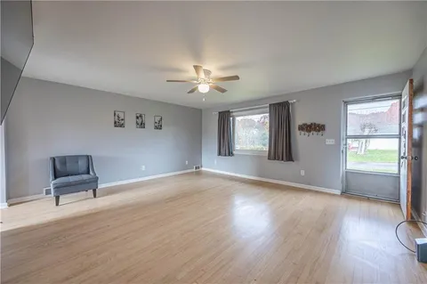 a view of an empty room with a window and wooden floor
