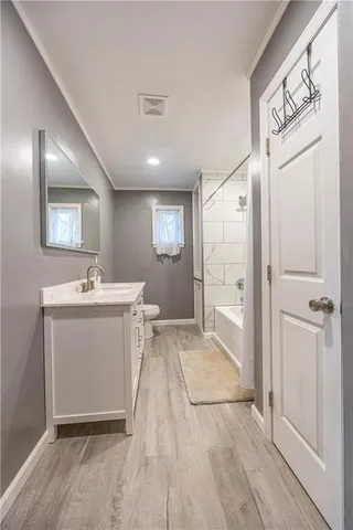 a view of a hallway with wooden floor and a bathroom