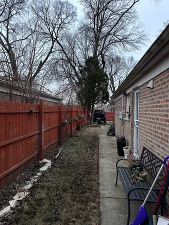 a view of backyard with wooden fence and large trees