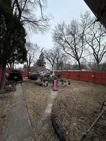 a view of backyard with wooden fence and large trees