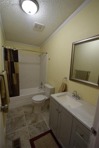 287 Anderson Road Florissant, CO 80816 - Photo 15 of 17 Full bathroom with shower / bath combo, toilet, tile flooring, ornamental molding, and vanity