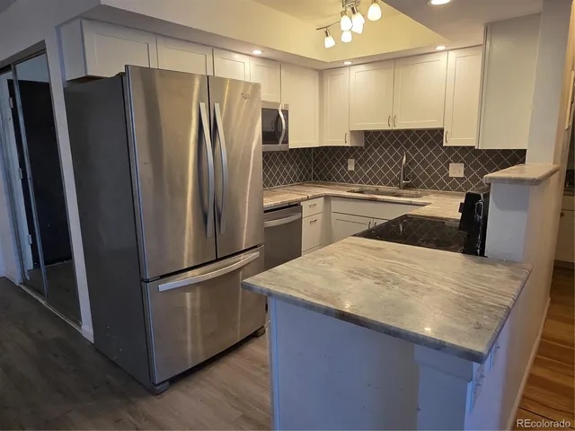 a kitchen with granite countertop a refrigerator and a sink