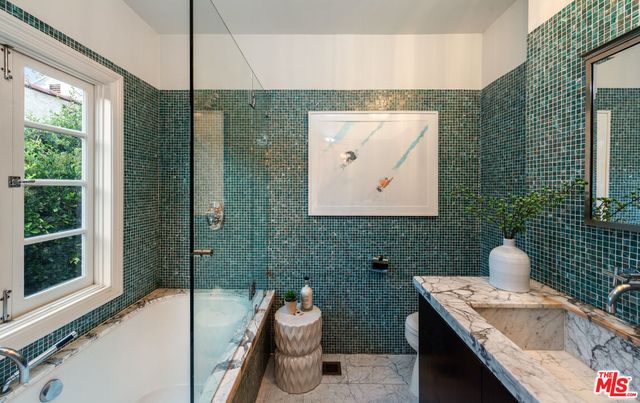 a bathroom with a tub sink and mirror