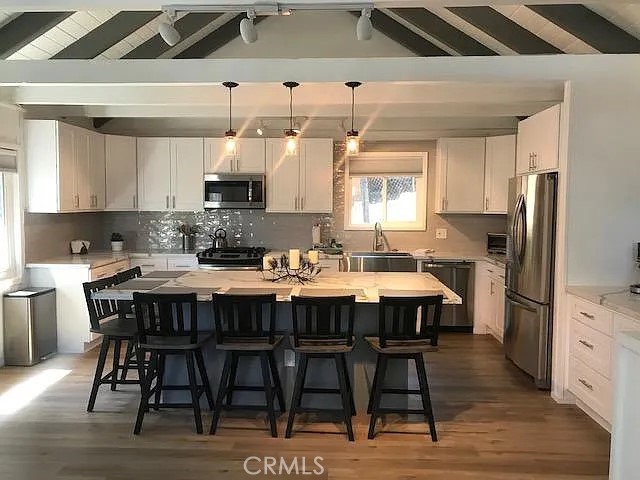 a kitchen with stainless steel appliances a table chairs sink refrigerator and cabinets
