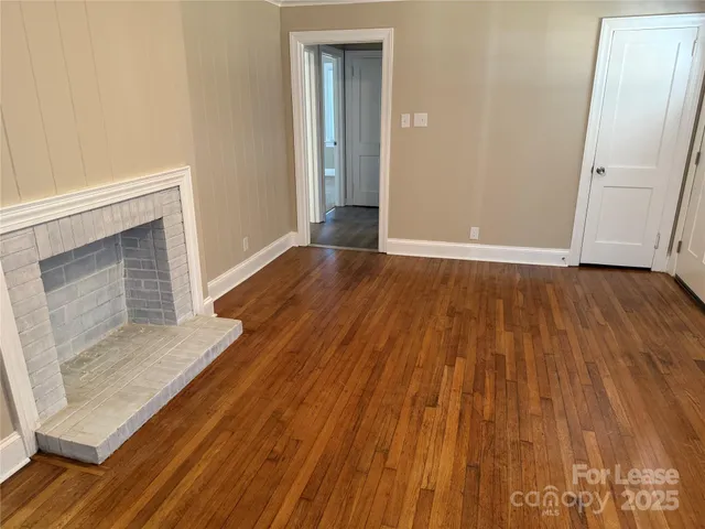 a view of an empty room with wooden floor and a fireplace