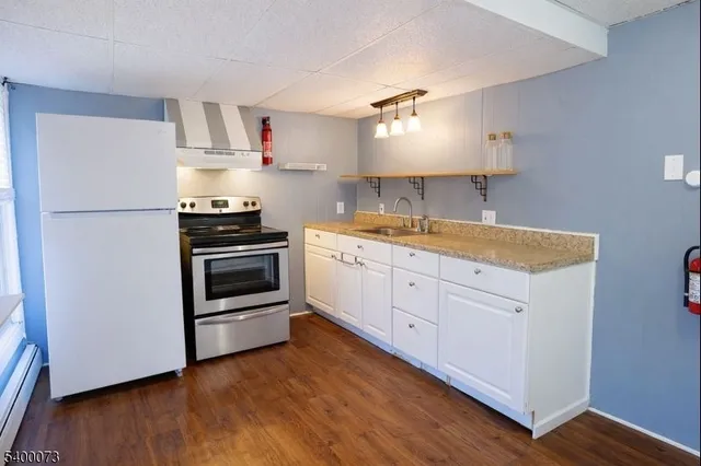 a kitchen with white cabinets stainless steel appliances and wooden floor
