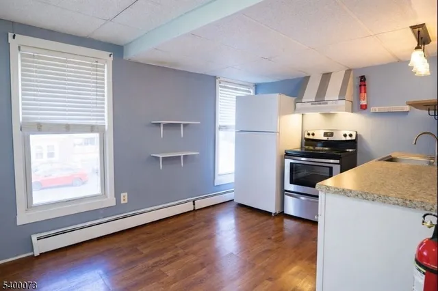 a kitchen with granite countertop a refrigerator and a stove top oven