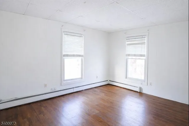 an empty room with wooden floor and window