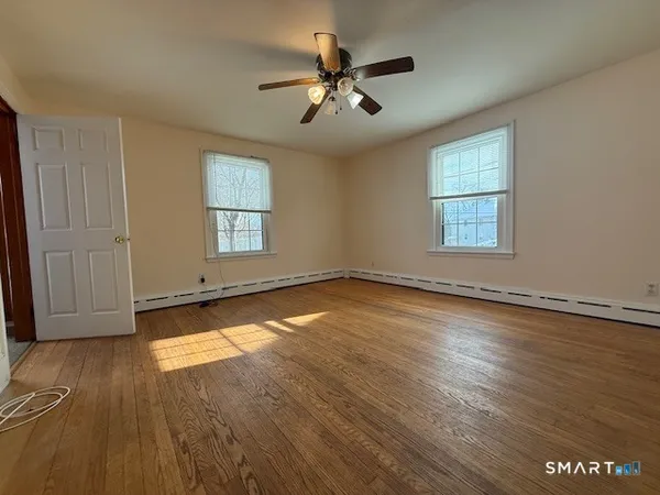 an empty room with wooden floor and windows
