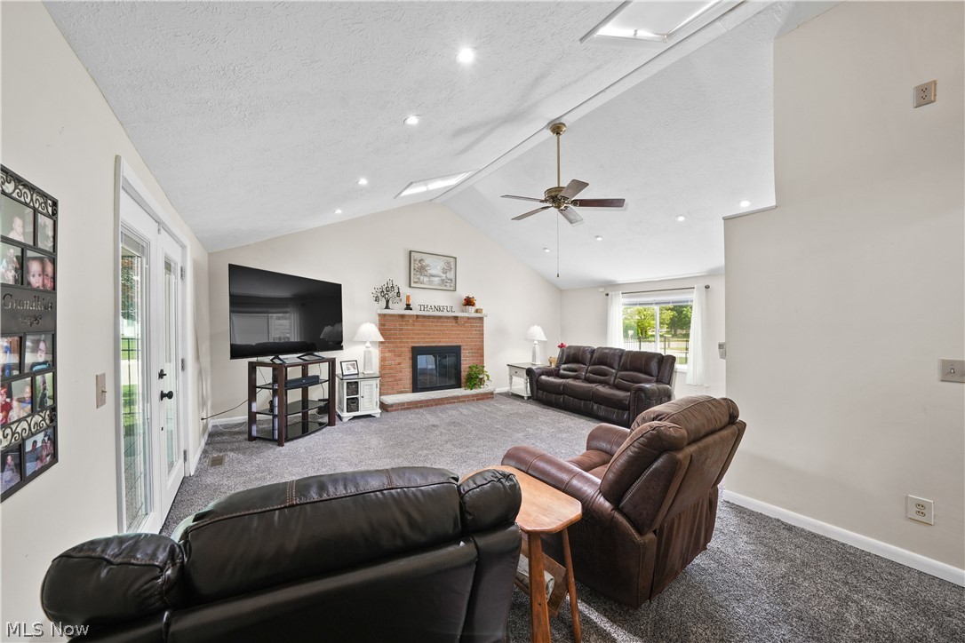 11247 Prospect Road Strongsville, OH 44149 - Photo 14 of 49 Living room with a textured ceiling, a fireplace, lofted ceiling, carpet floors, and ceiling fan