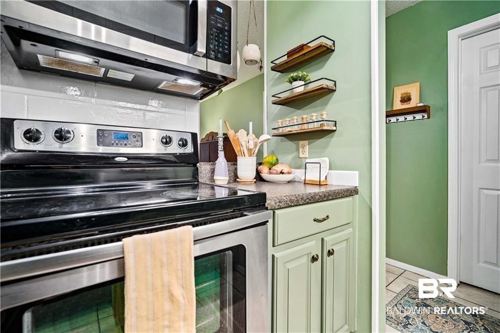 Kitchen featuring light tile patterned flooring, a textured ceiling, and appliances with stainless steel finishes