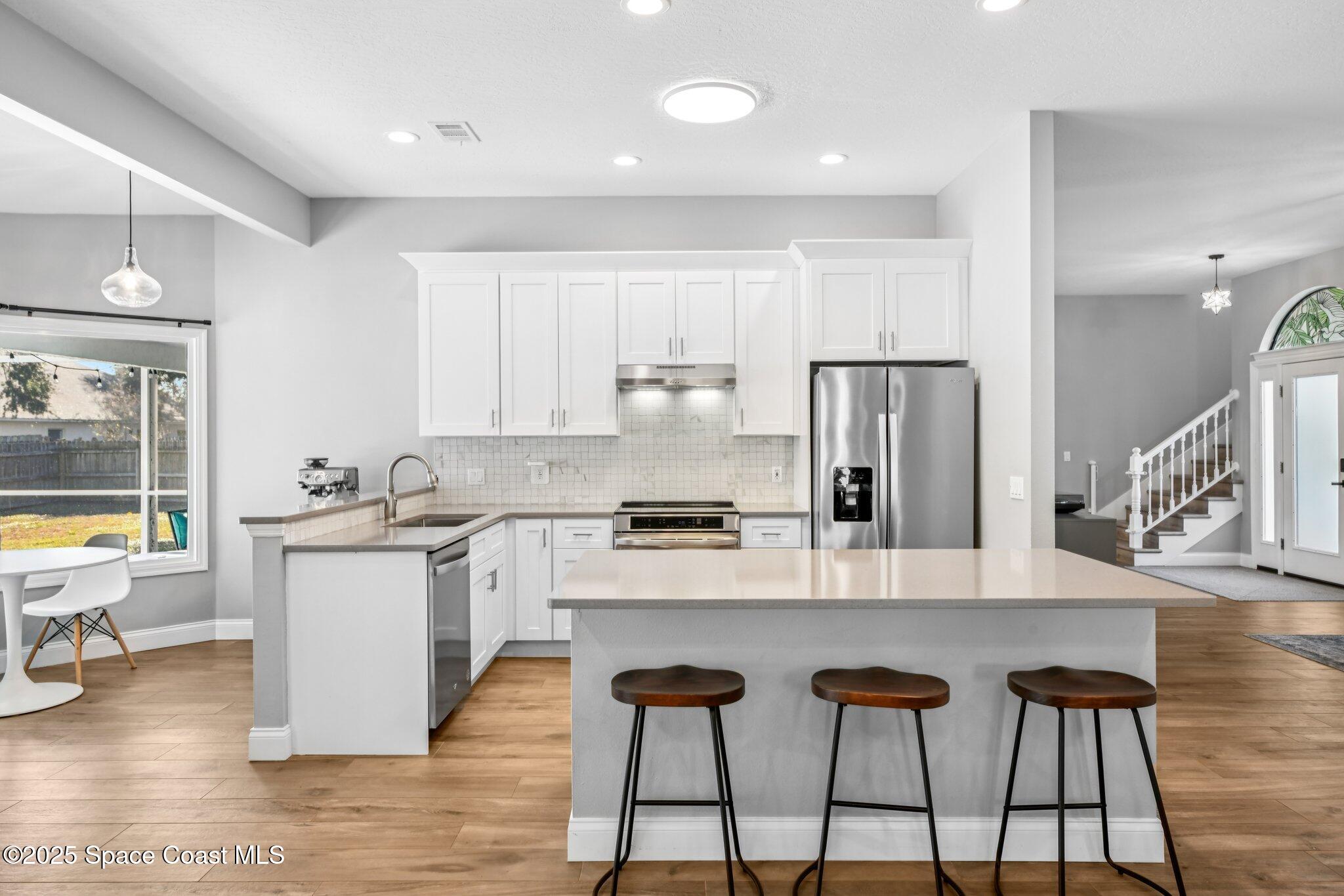 1935 Gates Road Merritt Island, FL 32952 - Photo 13 of 54 a kitchen with stainless steel appliances granite countertop a stove top oven a sink dishwasher and white cabinets with wooden floor