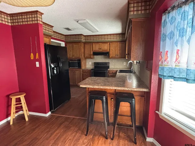 a kitchen with stainless steel appliances granite countertop a table chairs in it and wooden floors