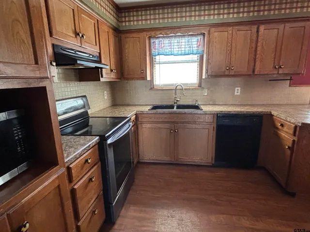 a kitchen with stainless steel appliances granite countertop a stove a sink dishwasher and a microwave oven on the wooden cabinets