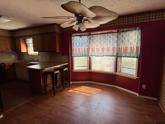 a kitchen with granite countertop a stove a sink a window and wooden floor