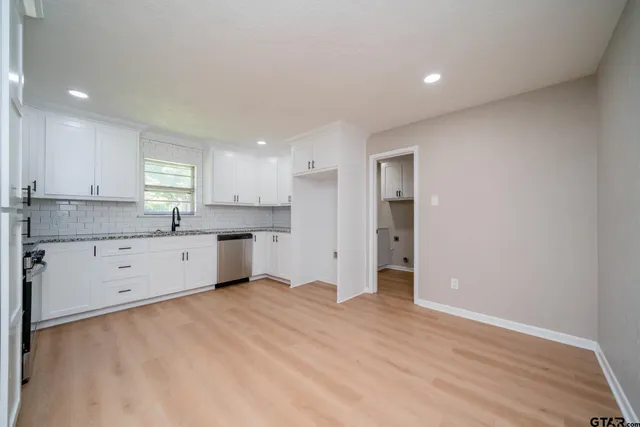 a kitchen with granite countertop white cabinets and refrigerator