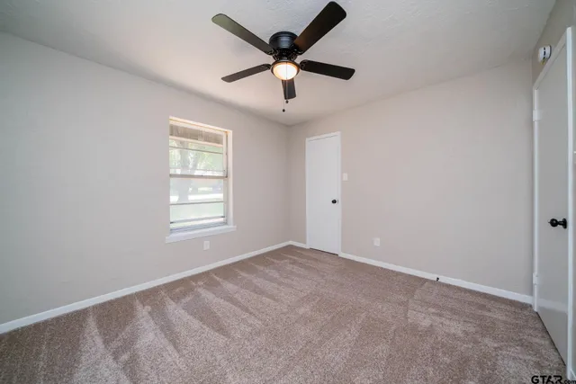 a view of an empty room with window and a ceiling fan