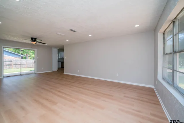 an empty room with wooden floor and windows