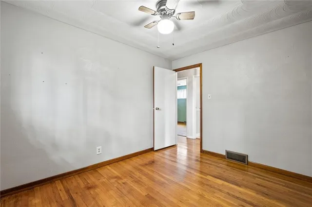 an empty room with wooden floor and fan