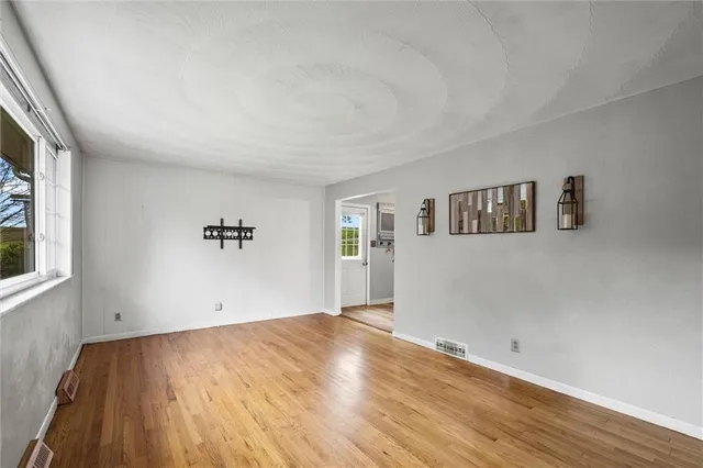 a view of a big room with wooden floor and windows
